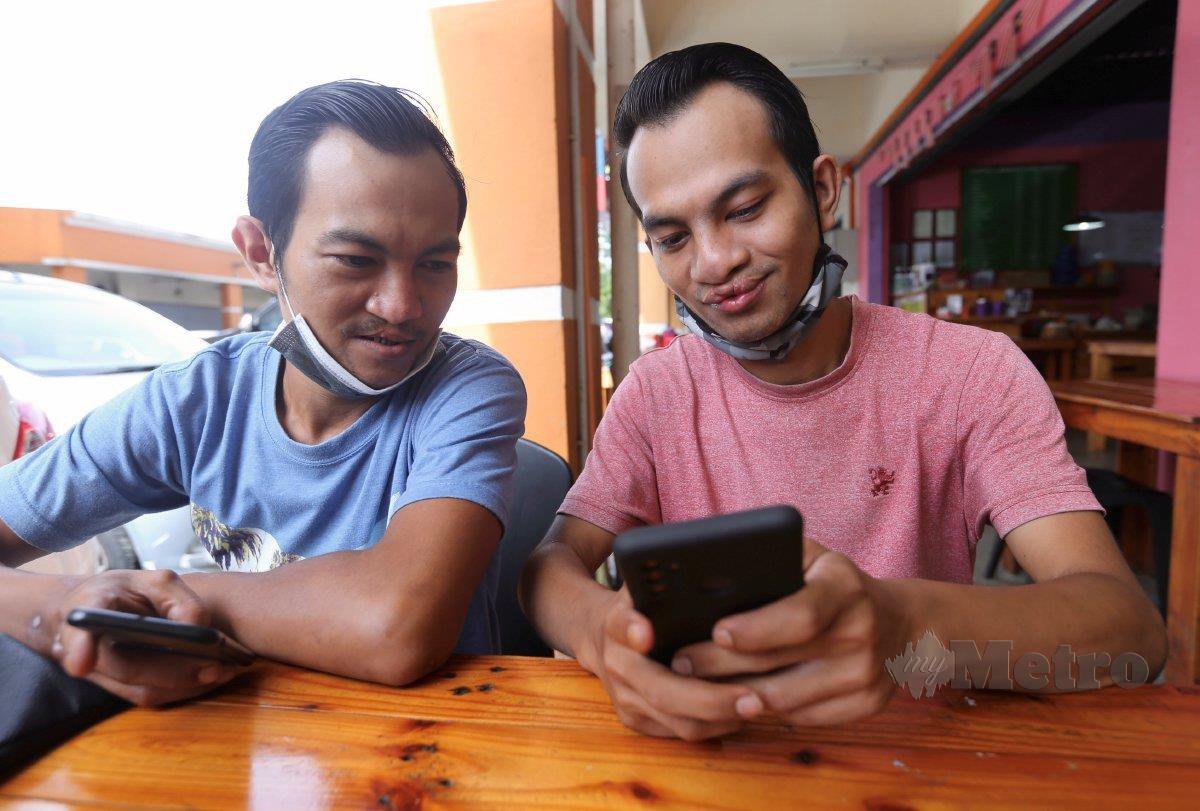 AMIRUL Hafizan (kiri) bersama Mohamad Syafiq Haikal mencari rezeki sebagai penghantar makanan sejak diberhentikan kerja Mac lalu. FOTO Fathil Asri